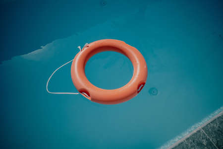 in the blue water of a swimming pool floats a red life ringの写真素材