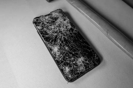 next to a completely destroyed cell phone lies a hammerの写真素材