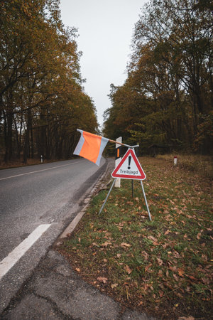 on the side of the road there is a sign with a flag with the warning Attention Drift Huntingの写真素材