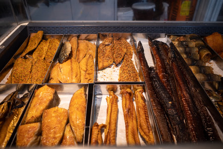 some different kinds of smoked fish lie in the display of a storeの写真素材