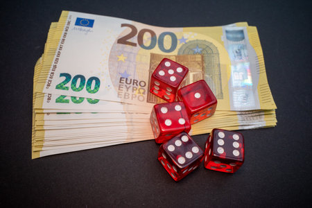 Red dice lay on a stack of two hundred euro banknotesの写真素材