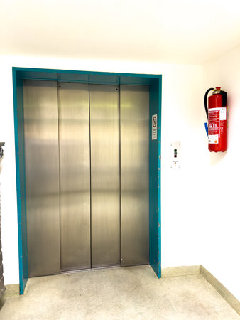 next to the elevator hangs a large red hand fire extinguisher
