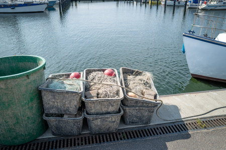 in the port there are fishing nets in containers next to the fishing boatの写真素材