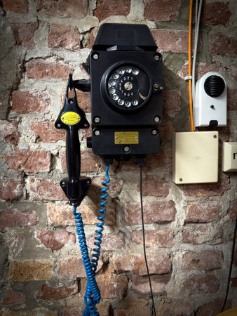on the wall hangs an old dial telephoneの写真素材