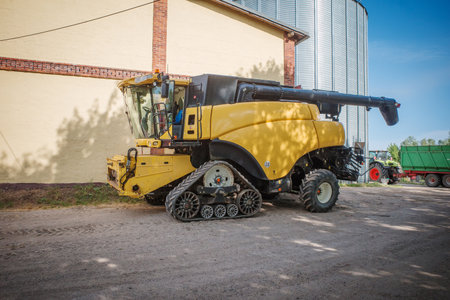 a huge yellow combine harvester stands on a farm