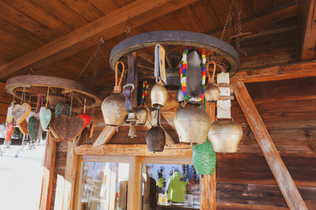A rustic alpine interior detail featuring traditional cowbells and decorative wooden hearts hanging...