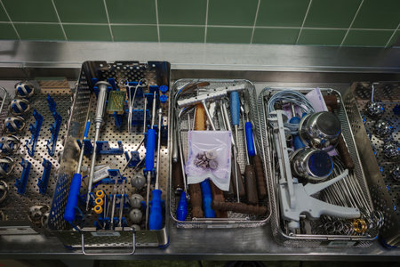 A top-down view of sterilized surgical instruments neatly arranged in metal trays on a stainless steel work surface in a hospital operating room. The image shows orthopedic and surgical tools prepared for a medical procedure, emphasizing precision, hygiene, and professional healthcare standards. This scene represents modern surgery, medical technology, and clinical preparation, making it ideal for topics such as healthcare, surgery, hospital equipment, and medical workflows.の写真素材