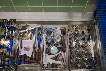 A top-down view of sterilized surgical instruments neatly arranged in metal trays on a stainless...