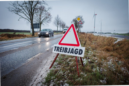 Warning road sign indicating â€œTreibjagdâ€ (driven hunt) placed along a rural roadside in...