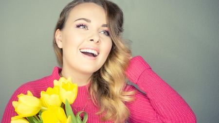 Young beautiful woman holding a bouquet of yellow tulips. Happy girl. Spring.の写真素材