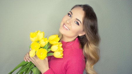 Young beautiful woman holding a bouquet of yellow tulips. Happy girl. Spring.の写真素材