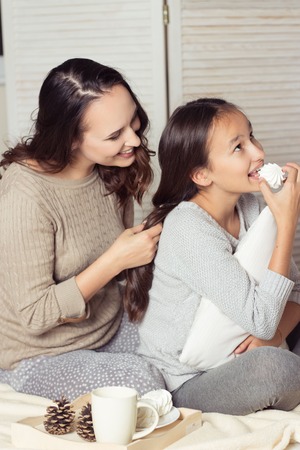 Mom and daughter secretive. Mom and daughter resting on the bed. Good morning. Cozy Fall. Winter.の写真素材