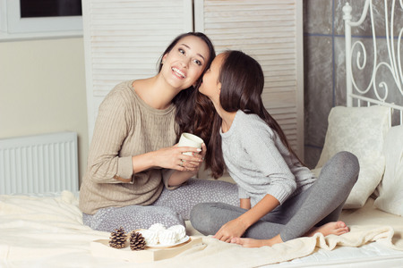 Mom and daughter secretive. Mom and daughter resting on the bed. Good morning. Cozy Fall. Winter.の写真素材