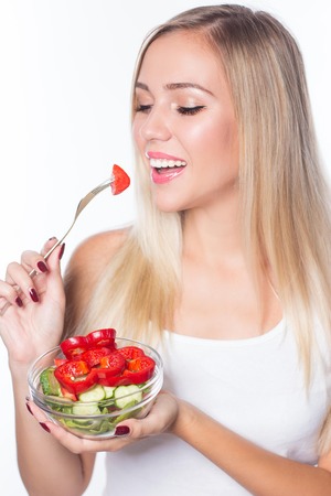 Young beautiful woman eats vegetable salad. Healthy eating. To be in shape.の写真素材