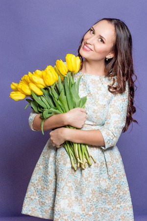 Young beautiful woman holding a bouquet of yellow tulips. Spring.の写真素材