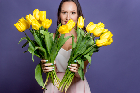 Young beautiful woman holding a bouquet of yellow tulips. Spring.の写真素材