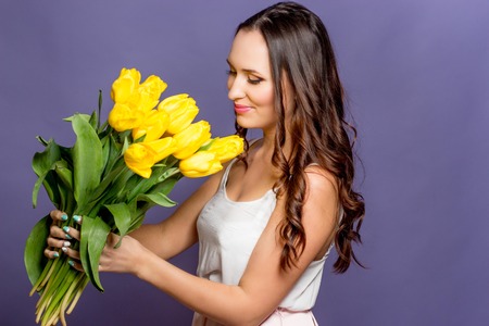 Young beautiful woman holding a bouquet of yellow tulips. Spring.の写真素材