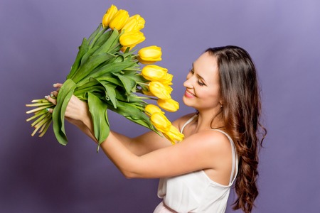 Young beautiful woman holding a bouquet of yellow tulips. Spring.の写真素材