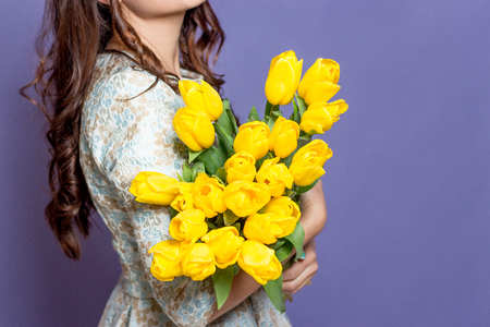 Young beautiful woman holding a bouquet of yellow tulips. Spring.の写真素材