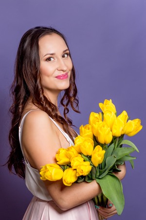 Young beautiful woman holding a bouquet of yellow tulips. Spring.の写真素材