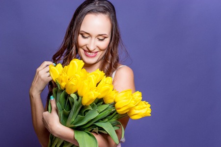 Young beautiful woman holding a bouquet of yellow tulips. Spring.の写真素材