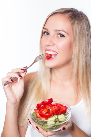 Young beautiful woman eats vegetable salad. Healthy eating. To be in shape.の写真素材