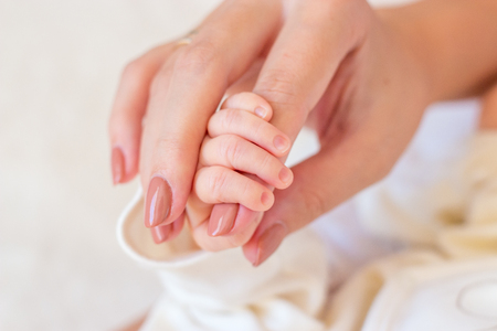 Close-up of legs, handles child. Happy mother kissing the feet, hands, fingers, the nose of the child. Gentle photo mom and baby.の写真素材