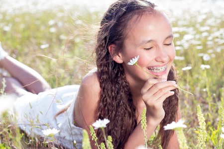 Happy girl walking in a field. Girl resting in a field of chamomile. Girl gathers daisies. Warm spring.の写真素材