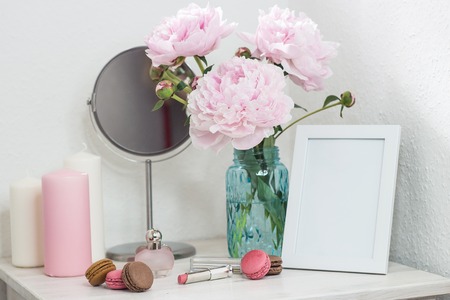 Bouquet of pink peonies in a vase. Bouquet of peonies in a vase, macaroon, cosmetics on the table. Dressing table.の写真素材