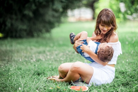Mother and young son played on grass. Mom and young son eating watermelon. Picnic. Summer.の写真素材