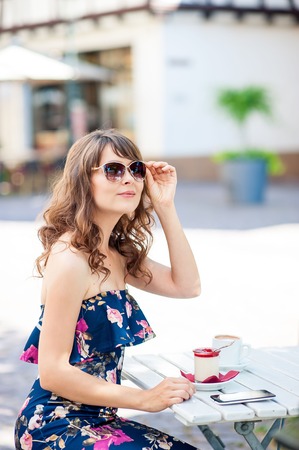 Beautiful young woman sits in a cafe. A girl drinks coffee and eats dessert. A young woman is walking around the city.の写真素材