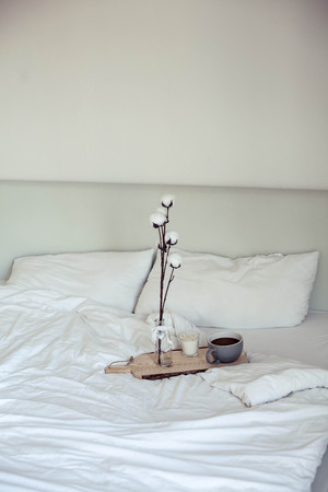Autumn cozy breakfast in bed. Romantic breakfast. Cotton, a cup of hot coffee, a candle. Autumn cosiness. A tray with breakfast is on the bed.の写真素材