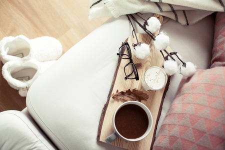 Autumn cozy breakfast. Romantic breakfast. Cotton, a cup of hot coffee, a candle, a plaid, glasses. Autumn cosiness. A tray with breakfast is on the couch. A cozy winter evening.の写真素材