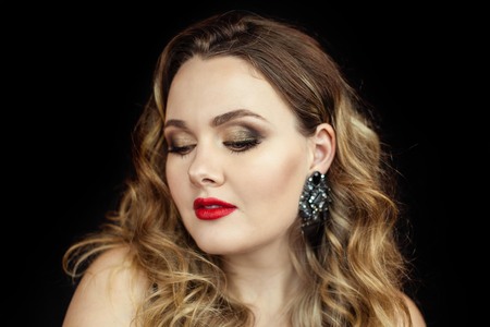 Portrait of a young beautiful woman with red lipstick on a black background. Makeup. Holidays. Beauty.の写真素材