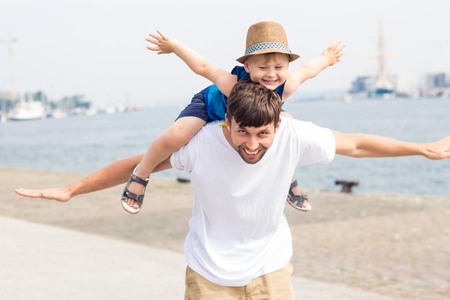Dad and son on the beach. Ocean. Summer. Happy dad and son are walking, looking at boats.の写真素材