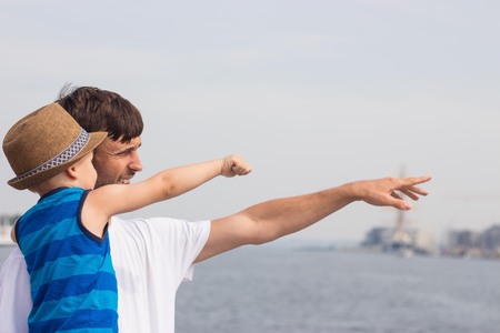Dad and son on the beach. Ocean. Summer. Happy dad and son are walking, looking at boats.の写真素材