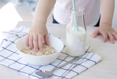 Cropped photo of a child eating his breakfast. Healthy food. Muesli, milk. Health. Children's hands and food.の写真素材