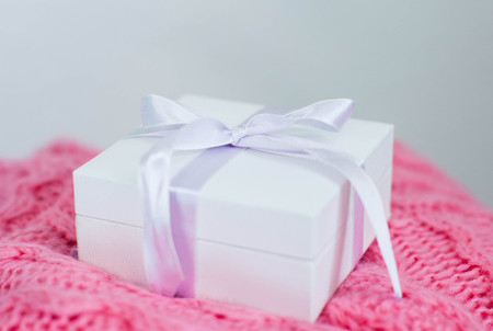 A white box with a gift lies on a knitted pink plaid. Spring. Birthday, holidays, mother's day. International Women's Day. Cozy.の写真素材