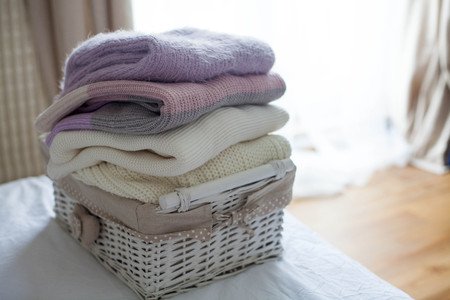 A basket with clean things on the bed. Cozy. Knitted sweaters. Fall. Spring.の写真素材
