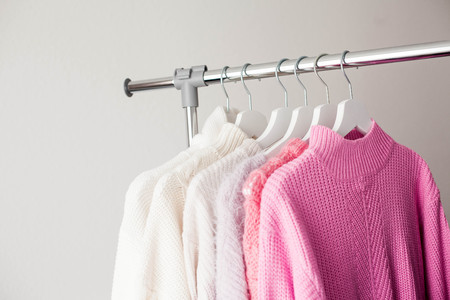 A hanger with things. Knitted sweaters hang on hangers. Bright sweaters. Spring clothes. Fashion. Cozy. Home. Springの写真素材