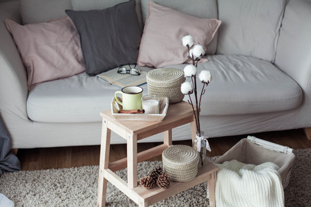 Home decor. A wooden bedside table, a sofa, a cotton, a mug of hot coffee, a knitted plaid. Warm house. Autumn. Cozy. House. The book and glasses. Interior. Springの写真素材