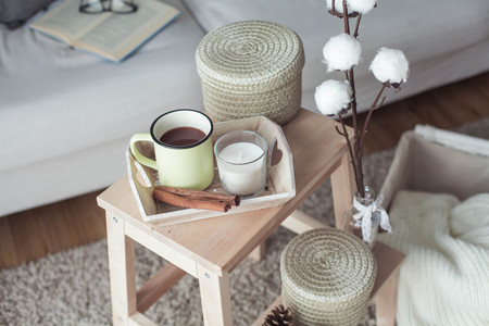 Home decor. A wooden bedside table, a sofa, a cotton, a mug of hot coffee, a knitted plaid. Warm house. Autumn. Cozy. House. The book and glasses. Interior. Springの写真素材
