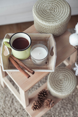 Home decor. A wooden bedside table, a sofa, a cotton, a mug of hot coffee, a knitted plaid. Warm house. Autumn. Cozy. House. The book and glasses. Interior. Springの写真素材