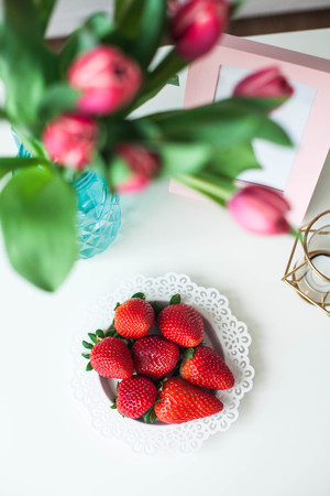 Interior. Coffee table, sofa, candle. A bouquet of tulips in a glass vase, strawberry. A room for rest. Bright hues. Spring. Cozy.の写真素材