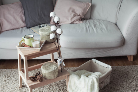 A wooden bedside table, a sofa, a cotton, a mug of hot coffee, a knitted plaid.の写真素材