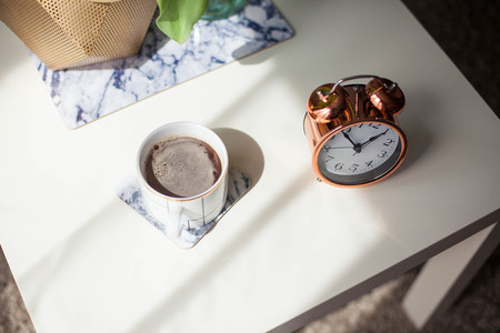 Interior. Room. A bouquet of tulips in a glass vase, a gold candlestick, a mug of hot coffee, an alarm clock on a white wooden table. Sofa, pillows. Spring. It's cozy.の写真素材