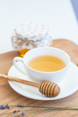 A cup of tea, lavender, a jar of honey stand on a wooden board. Bright hues. Cozy. Spring. Heat.の写真素材