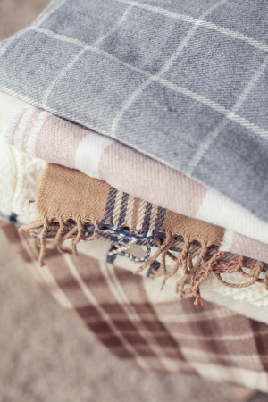 Plaids. Autumn cozy interior. A stack of warm blankets lie on a wooden chair. Autumn.の写真素材