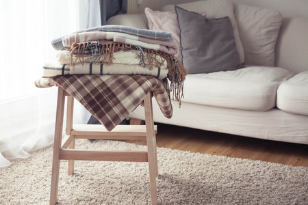 Plaids. Autumn cozy interior. A stack of warm blankets lie on a wooden chair. Autumn.の写真素材