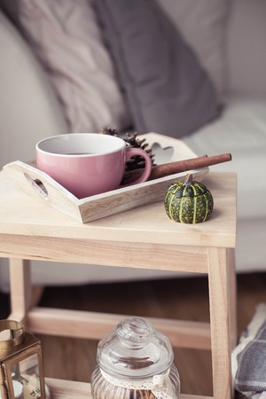Plaids, a cup of hot tea, autumn decor, a book, a pumpkin on a wooden chair. Cozy, autumn decor. Autumn interior, sofa. Fall. Winter.の写真素材